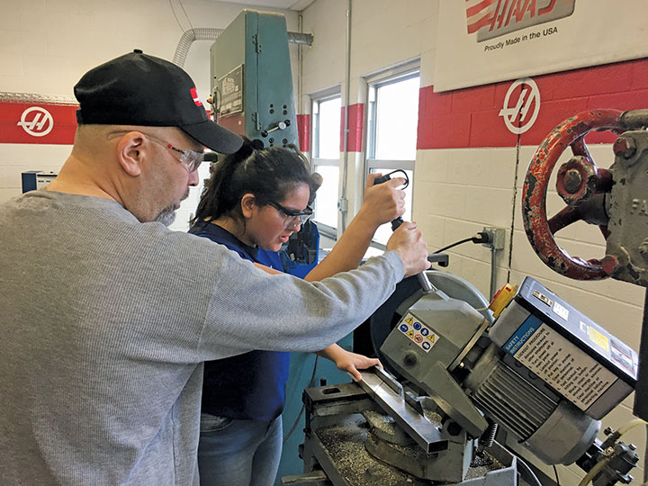 Consultant instructor Sal Ligitino coaches Heidy Cardenas-Ruballos in her first attempt at cutting a part for the robot.