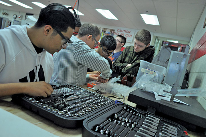 Erik Augustin-Santos, Juan Neri-Ramos, Maxwell Roque, and Matthew Albert organize tools and work on electrical elements of the robot.