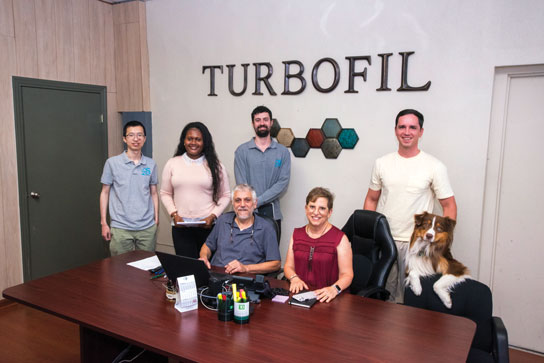 TurboFil principles Eli Uriel and Deborah Smook meet with team members at the companys Mount Vernon headquarters accompanied by the official TurboFIl Team Mascot Teddy